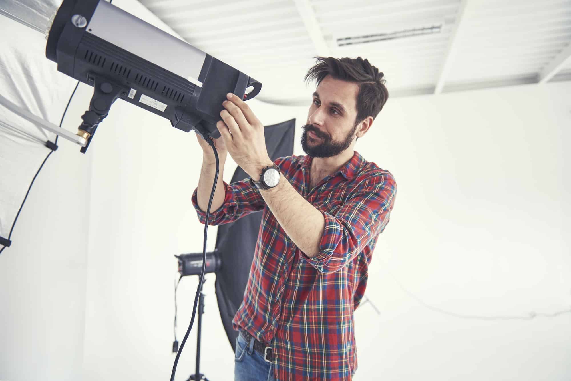 Male photographer preparing photo shoot lighting equipment in studio